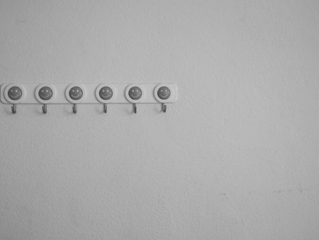 Multiple hangers with smiley face on white wallの写真素材