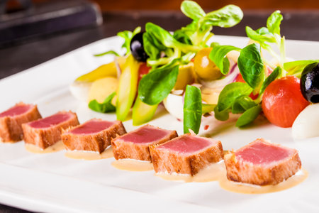Nicoise salad with tuna, vegetables and herbs on white plateの写真素材