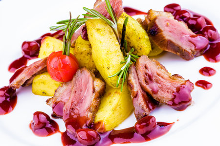 Duck breast with berry sauce and baked potato on white plateの写真素材