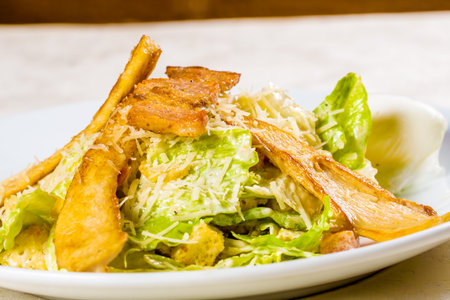 Caesar salad with chicken and parmesan cheese on white plateの写真素材