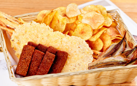 Assorted snacks for beer: sun dried fish, potato chips, salted crackers, rye bread croutons in...