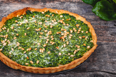 Tart with spinach, ricotta cheese and pine nuts on wooden rustic table. Close upの写真素材