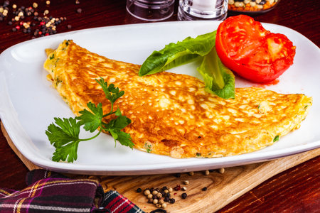 Breakfast. Omelette with tomato and parsley on white plate.