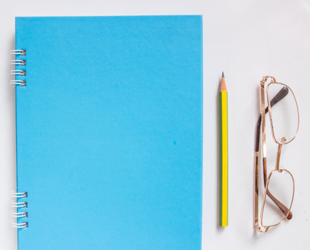 Blank book cover with pencil and eyeglass on board.の写真素材