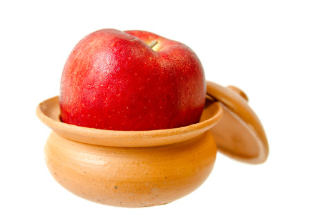 Closeup shot of fresh apple in clay pot on white isolated.の写真素材