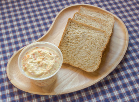 Shot of wholewheat sliced bun and sandwich-spread in cup.の写真素材