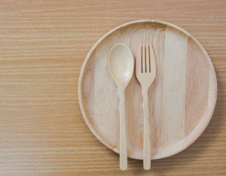 Wooden plate with spoon and fork made from natural wood on wood table,top view shot.の写真素材