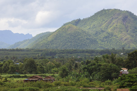 Landscape, Field and forest against the big mountain and cloudys sky.の写真素材