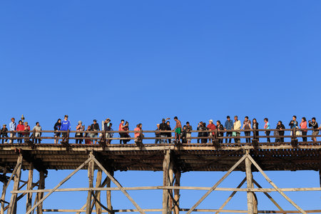 Sangkhlaburi, Thailand - February 14, 2016: Crowd of tourist are enjoying on wooden bridge against clear blue sky.のeditorial素材