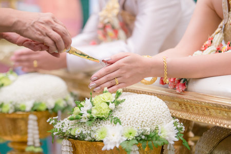 Hand of a bride receiving holy water from elders in thai culture wedding ceremony.の写真素材