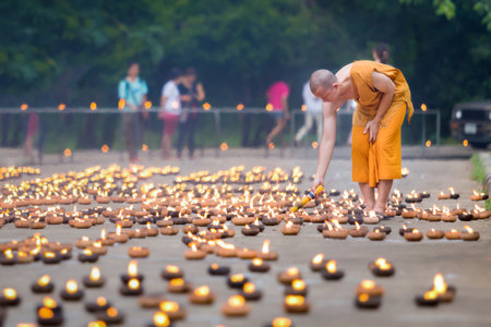 Kanchanaburi, Thailand - July 19, 2016: Portrait of monks lighting up candlelight inside a Buddhist...