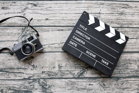 Vintage camera and slate or clapper board on wood print tablecloth background.の写真素材