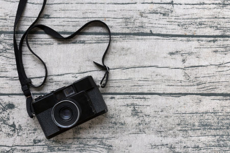 Black vintage camera on old wood print tablecloth background. Top view and copy space.の写真素材