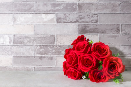 Artificial red rose flower bouquet on table gray brick wall background.の写真素材