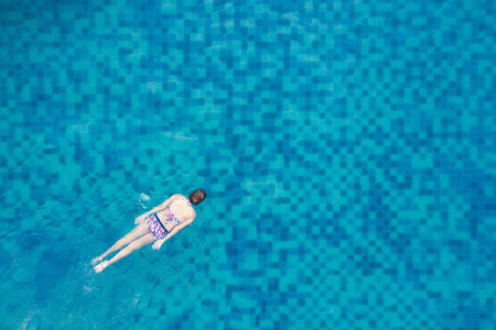 Aerial top view of woman in swimming pool water from above, tropical vacation holiday concept.の写真素材