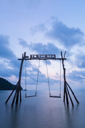 Summer holiday vacation time the wooden swing on the beach in front of the blue sea.の写真素材