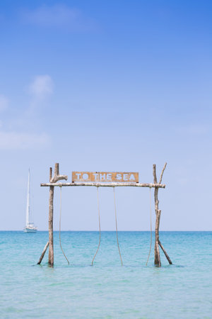 Summer holiday vacation time the wooden swing on the beach in front of the blue sea.の写真素材
