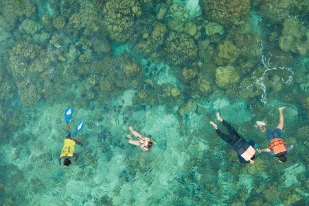 Group of tourists are swimming in blue sea. Snorkeling in full-face snorkeling mask. Coral reef in shallow sea. Snorkel undersea. Seashore underwater photo. Active seaside vacation.の写真素材