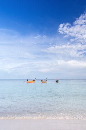 Vertical image of wooden Thai traditional longtail boat on white sand beach at Lipe Island, Satun, Thailand.の写真素材