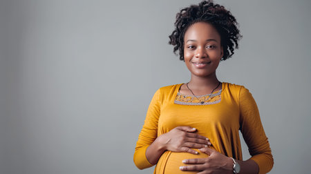 Happy young pregnant african american woman touching belly on grey background. AI Generated.の素材