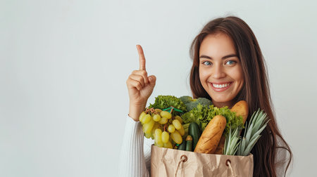 Young woman is holding healthy groceries in paper bag from supermarket pointing and showing with thumb up to the side with happy face smiling on isolated white background. AI Generated.の素材
