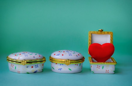 Jewelry boxes with one having a red heart inside on blue backgroundの写真素材