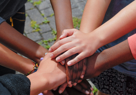 Multiracial teen friends joining hands together in cooperationの写真素材