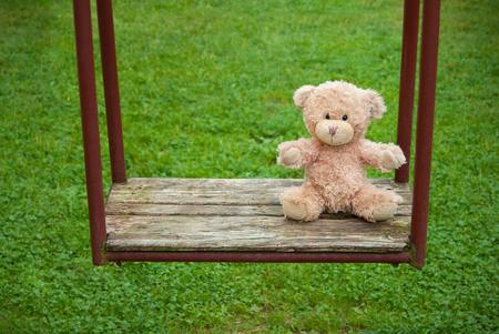 Teddy bear sitting on the swing. Loneliness concept.の写真素材
