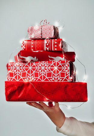 Womans hand holding a pile of nicely packed christmas gifts on white backgroundの写真素材