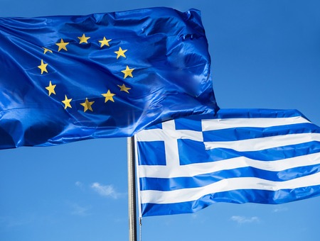 Greek and European Union flags waving in blue skyの写真素材