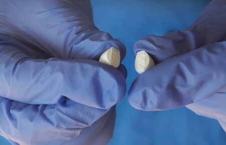 Nurse holding white pills with protective gloves