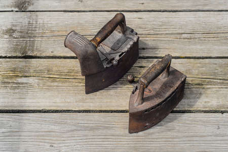 Old antique irons on vintage wooden backgroundの写真素材