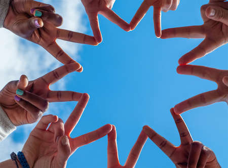 Black and white people forming nine pointed star with their fingers.の写真素材