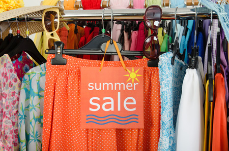  Close up on a big sale sign for summer clothes  Clearance rack with colorful summer outfits and accessories displayed on hangers の写真素材