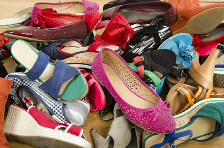 Close up on big pile of colorful woman shoes. Untidy stack of shoes thrown on the ground.