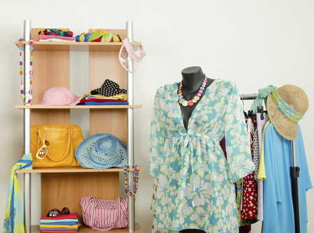 Dressing closet with colorful clothes and accessories on hangers and a shelf.の写真素材