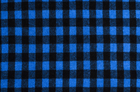 Closeup on checkered tablecloth wool fabric. Blue with black gingham square pattern as background.の写真素材