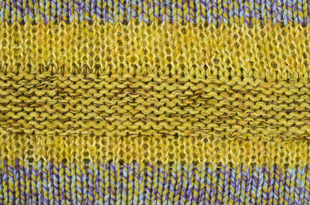 Close up on knit woolen texture. Olive green and blue woven thread sweater as a background.