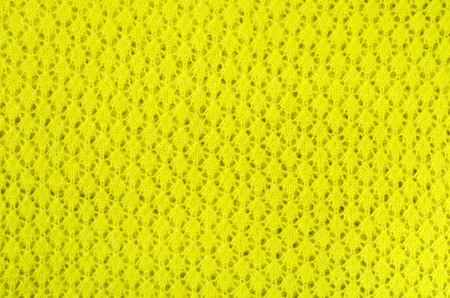 Close up on knit woolen texture. Neon yellow woven thread as a background.