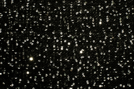 Silver sequins pattern. Sparkling sequins on black wool fabric as background.の写真素材