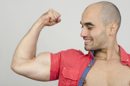 Bodybuilder showing his biceps muscles. Fit man posing with his arm up showing his biceps.