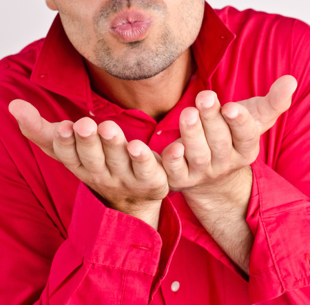 Romantic man blowing a kiss dressed in red shirtの写真素材