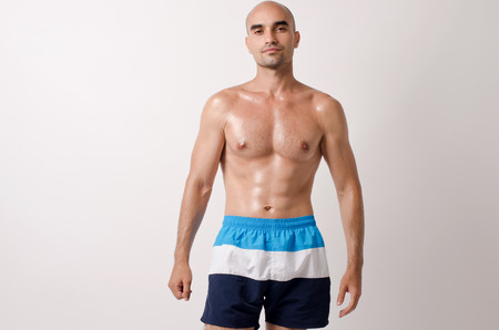 Fit bodybuilder showing his body. Topless man in shorts with trained muscles.の写真素材