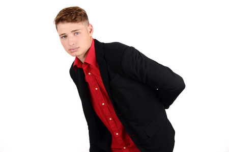 Young business man holding his back in pain wearing a suit and a red shirt. Isolated on white.の写真素材