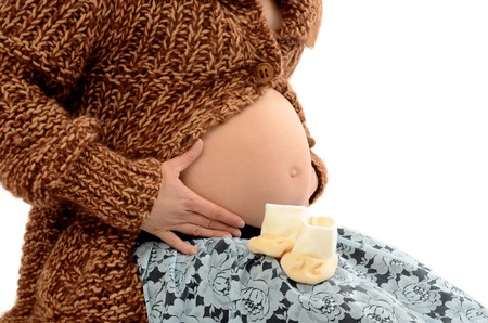 Close up on pregnant belly. Woman expecting a baby holding the belly and a cute pair of new born...