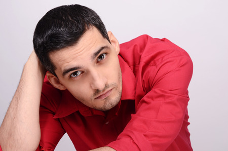 Handsome man posing looking up at the camera. Portrait of a young business man wearing a red shirt.の写真素材
