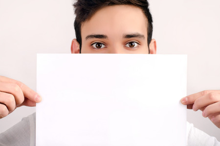 Eyes looking over a piece of paper. Man holding a blank white paper.