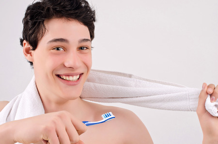 Morning routine of washing the teeth. Handsome young man with beautiful teeth smiling and holding a toothbrush.の写真素材