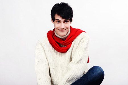 Portrait of a handsome man dressed for a cold winter smiling. Man wearing a white sweater and red scarf.の写真素材