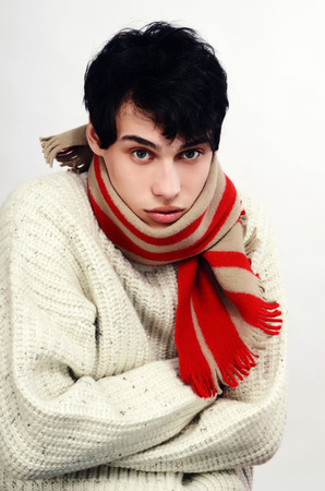 Portrait of a handsome man dressed for winter feeling cold. Man wearing a sweater and scarf.の写真素材